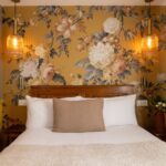 welcome hotel rive gauche paris : lit, coussin, tissu jaune fleuri et photos en noir et blanc de Paris